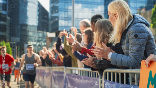 Marathon Audience Supporting and Cheering Their Loved Ones Participating in the Race: Athletic Male Marathon Runner Cheered by Female Family Member in the Audience While Running