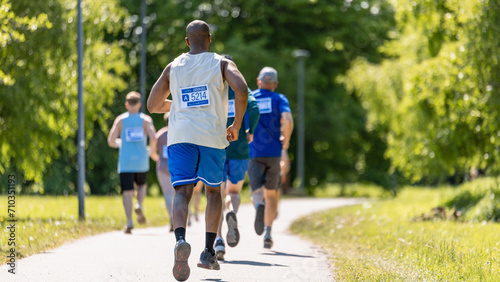 Fototapeta Naklejka Na Ścianę i Meble -  Back View of Diverse Marathon Participants Competing in a Race for the Finish Line: Group of People Running Through Park Health Trail and Participating in a Marathon with Dedication