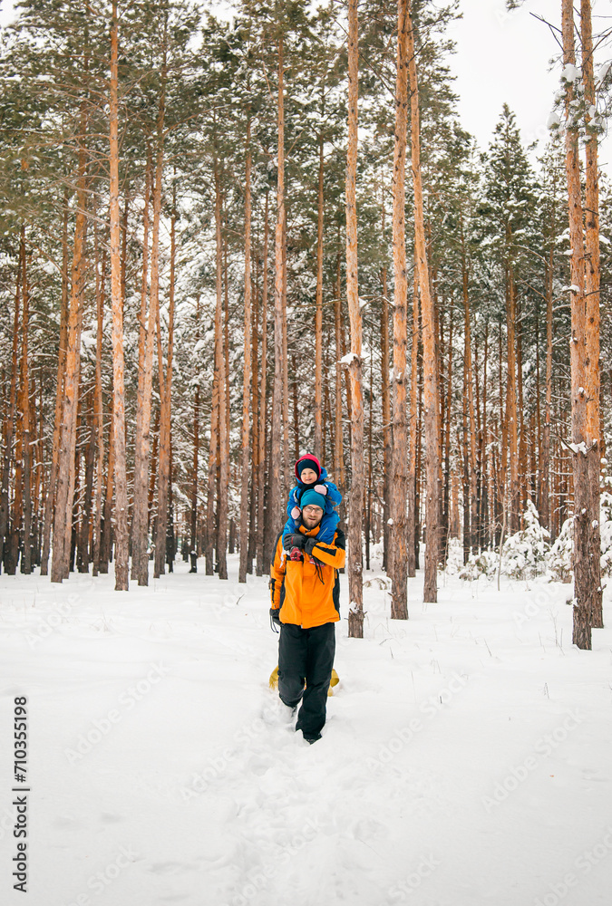 Family leisure. Father walks with his children in snowy forest on clear day. Recreation in the fresh air.