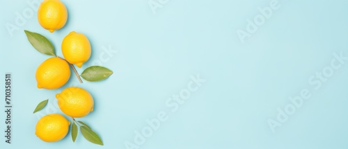 A diagonal line of fresh yellow lemons with leaves on a blue background