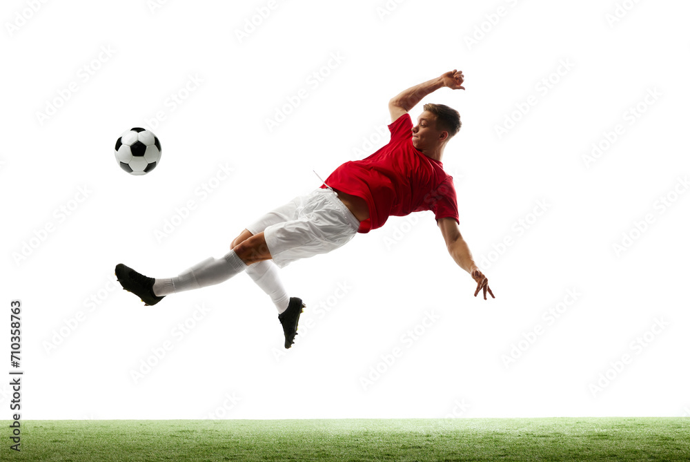 Elevated excellence. Soccer maestro kicks ball into air, showcasing skill and finesse against white studio background with green grass. Concept of sport games, energy, world cup season, movement. Ad