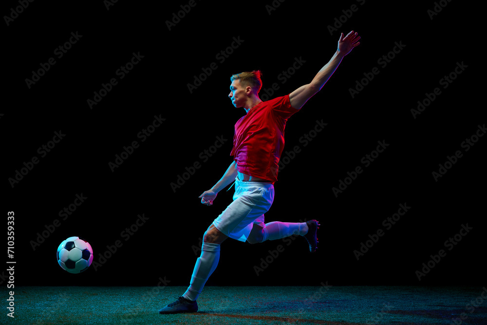 Precision in Motion. skilled football player delivers perfect airborne pass, showcasing unparalleled precision against black background in neon light. Concept of sport games, world cup season, match.
