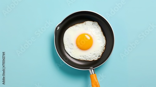 Above image of fried egg on blue skillet next to raw egg and eggshells isolated on orange backdrop