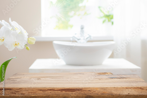 Wooden table top with copy space on blurred bathroom sink and window background