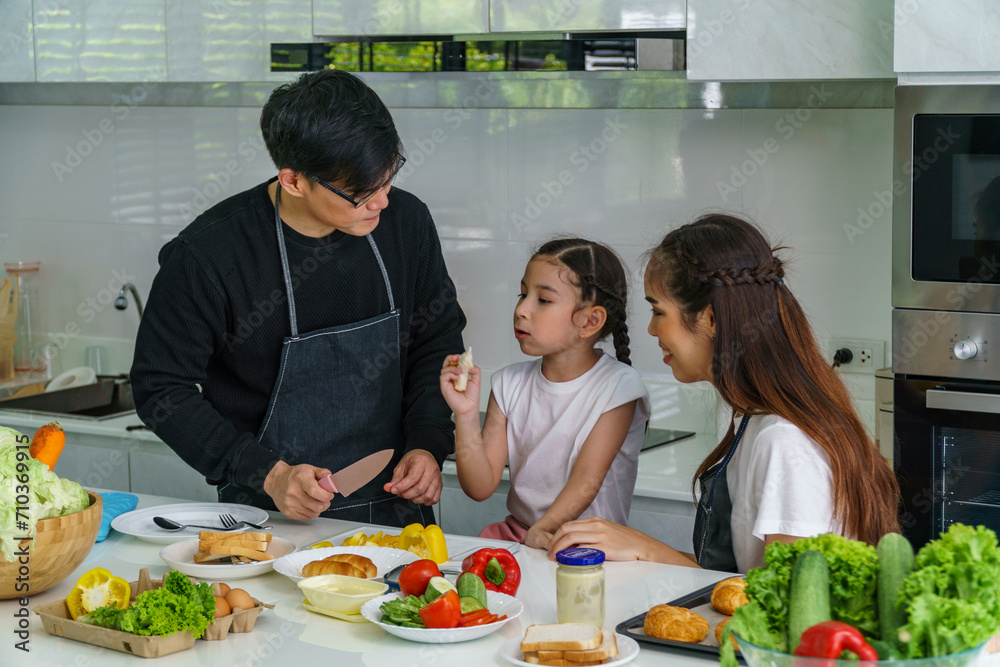 Father, mother and daughter are cooking in the kitchen inside the house. with fun Father, mother and daughter are cooking in the kitchen inside the house. with fun