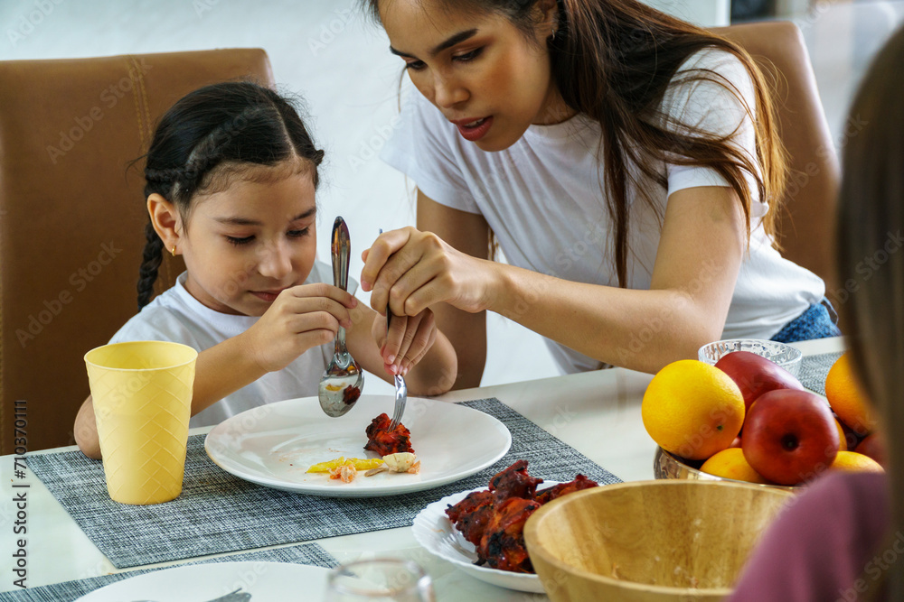 Mother feeds little girl family eating on the dining table inside the house Mother feeds little girl family eating on the dining table inside the house