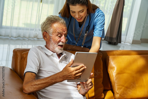 Nurse in a nursing home Advising an old man to use tablets in the living room