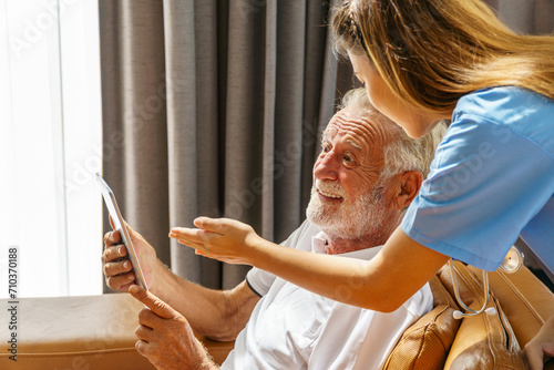 Nurse in a nursing home Advising an old man to use tablets in the living room