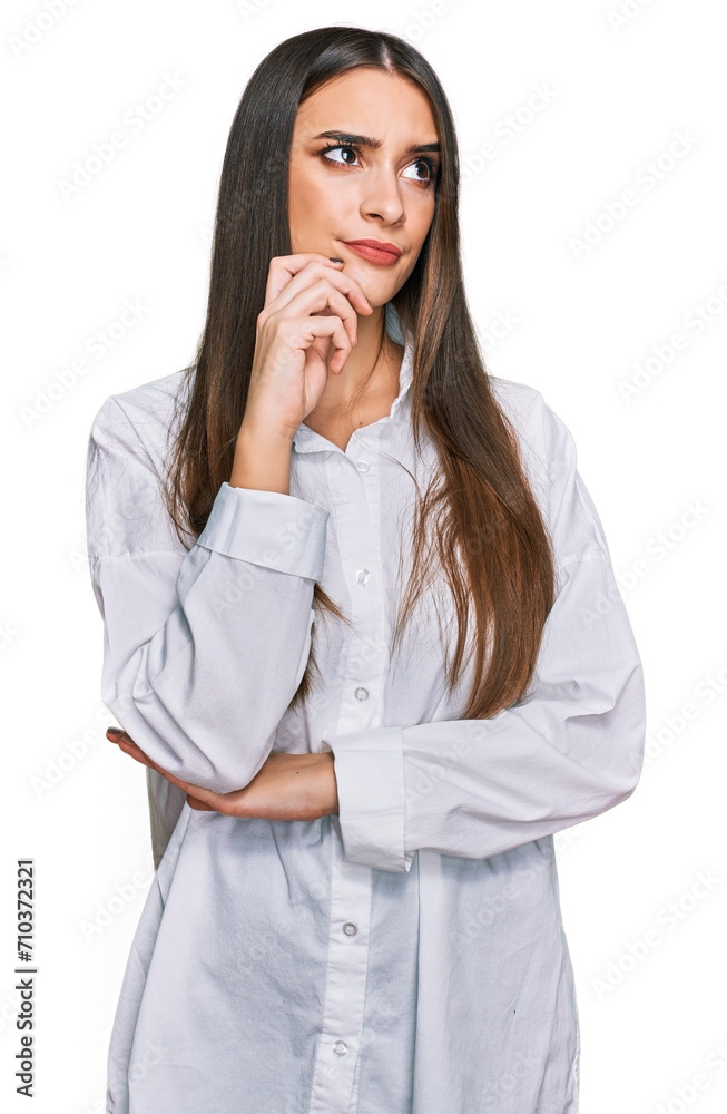 Young beautiful woman wearing casual white shirt serious face thinking about question with hand on chin, thoughtful about confusing idea Young beautiful woman wearing casual white shirt serious face thinking about question with hand on chin, thoughtful about confusing idea