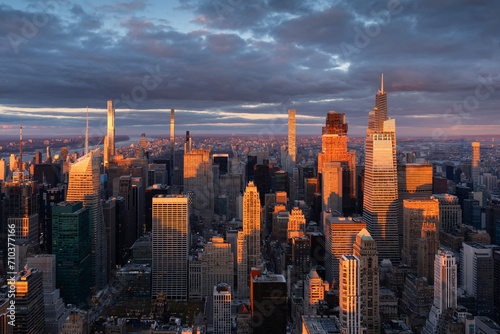 Midtown Manhattan supertall skyscrapers illuminated by warm light. Aerial view of New York City at sunset