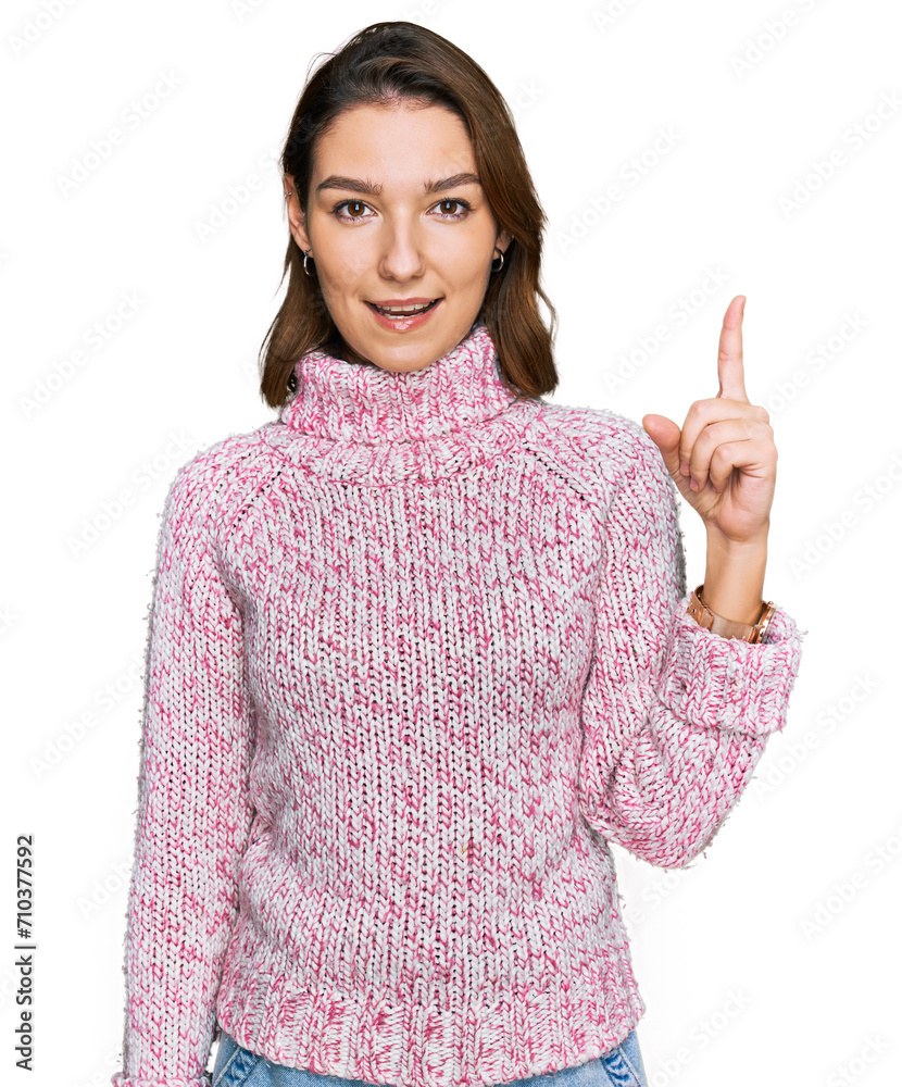 Young caucasian girl wearing wool winter sweater pointing finger up with successful idea. exited and happy. number one. Young caucasian girl wearing wool winter sweater pointing finger up with successful idea. exited and happy. number one.