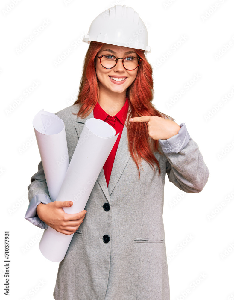 Young redhead architect woman wearing safety helmet holding blueprints pointing finger to one self smiling happy and proud Young redhead architect woman wearing safety helmet holding blueprints pointing finger to one self smiling happy and proud