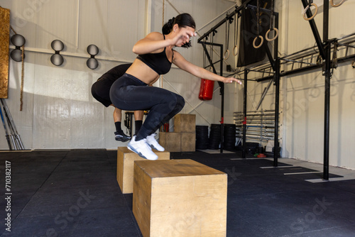 Fitness couple are performing box jumps at gym, plyometric exercise photo