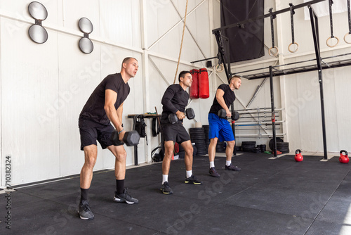 Group of fit man lifting dumbbells in the industrial gym