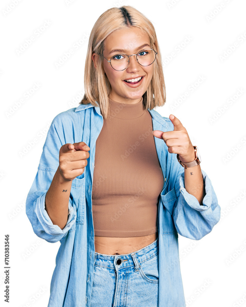 Beautiful young blonde woman wearing glasses pointing fingers to camera with happy and funny face. good energy and vibes. Beautiful young blonde woman wearing glasses pointing fingers to camera with happy and funny face. good energy and vibes.