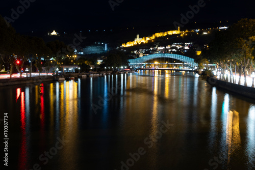 Panoramic landscape of downtown Tbilisi at night with church and bridge of peace