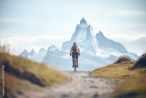 mountain biker on a trail with peaks in distance photo