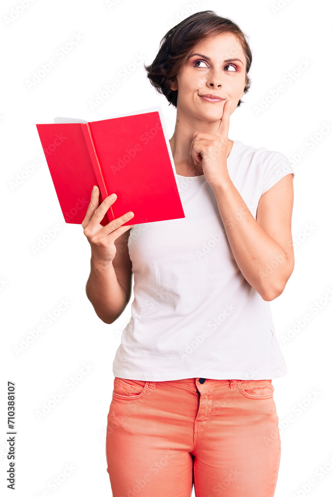 Beautiful young woman with short hair reading a book serious face thinking about question with hand on chin, thoughtful about confusing idea Beautiful young woman with short hair reading a book serious face thinking about question with hand on chin, thoughtful about confusing idea