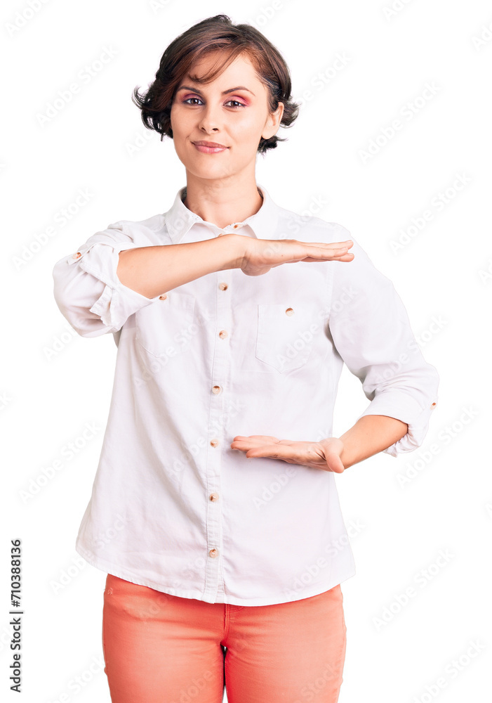 Beautiful young woman with short hair wearing elegant white shirt gesturing with hands showing big and large size sign, measure symbol. smiling looking at the camera. measuring concept. Beautiful young woman with short hair wearing elegant white shirt gesturing with hands showing big and large size sign, measure symbol. smiling looking at the camera. measuring concept.