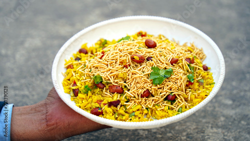 indian breakfast dish poha.Indian breakfast Poha topped with peanuts, pomegranate seeds, chopped green chilly, onion, lime, coriander leaves and curry leaves. photo