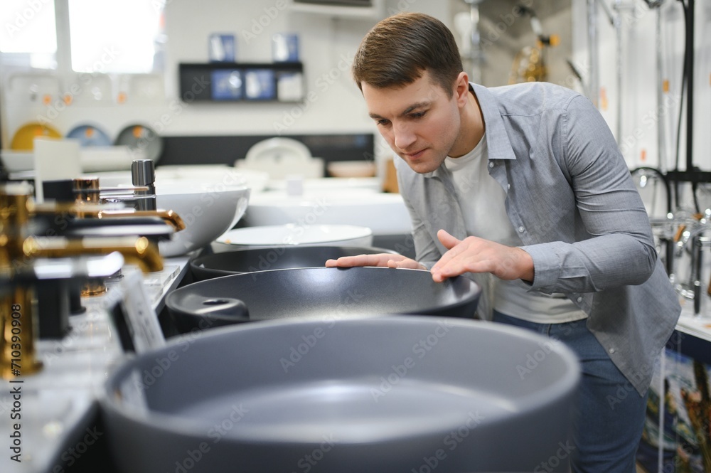 Man at the building market looking for sink into their bathroom Man at the building market looking for sink into their bathroom
