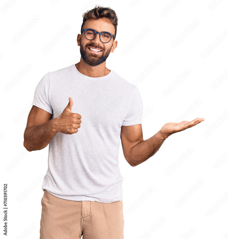 Young hispanic man wearing casual clothes and glasses showing palm hand and doing ok gesture with thumbs up, smiling happy and cheerful