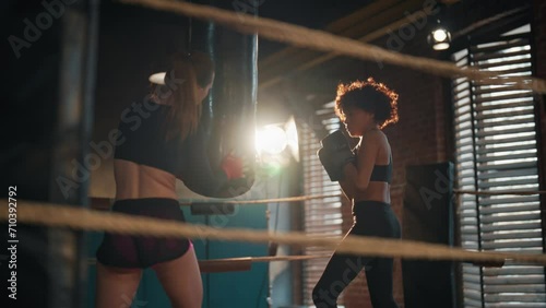 Two woman boxers boxing training. Coach sport trainer and young sportswoman in boxing gloves boxes and preparing to fight competition on boxing ring. Training, workout professional sport concept. photo