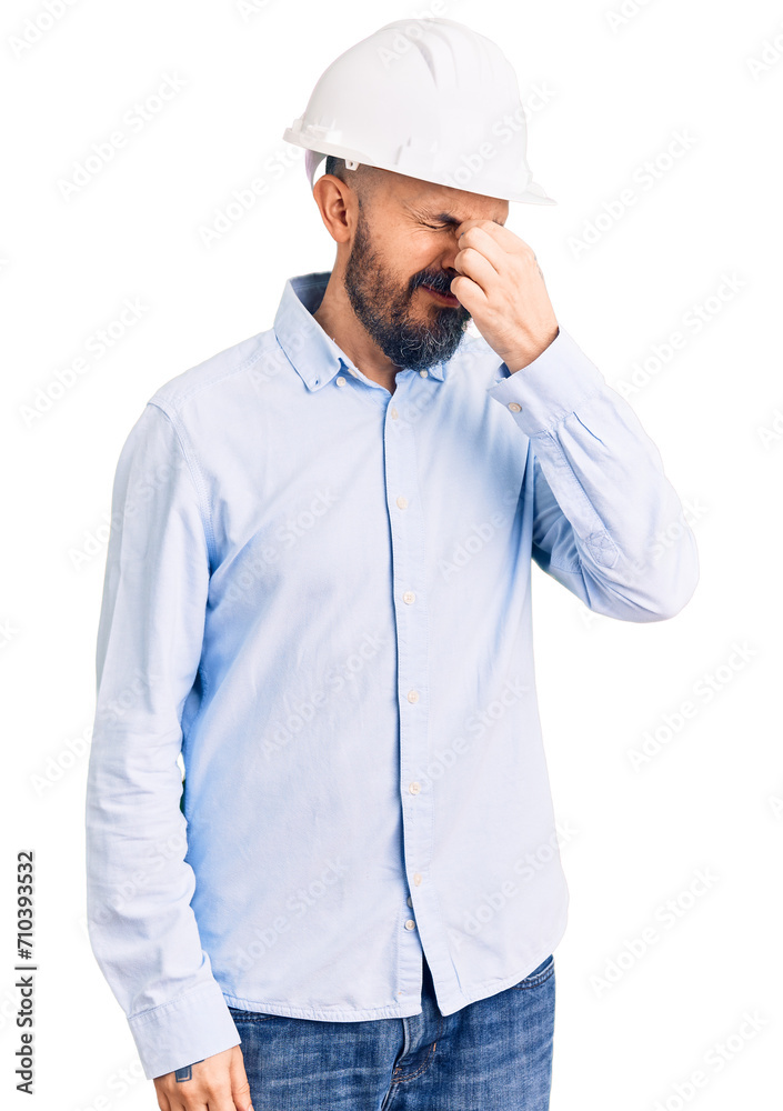 Young handsome man wearing architect hardhat tired rubbing nose and eyes feeling fatigue and headache. stress and frustration concept. Young handsome man wearing architect hardhat tired rubbing nose and eyes feeling fatigue and headache. stress and frustration concept.