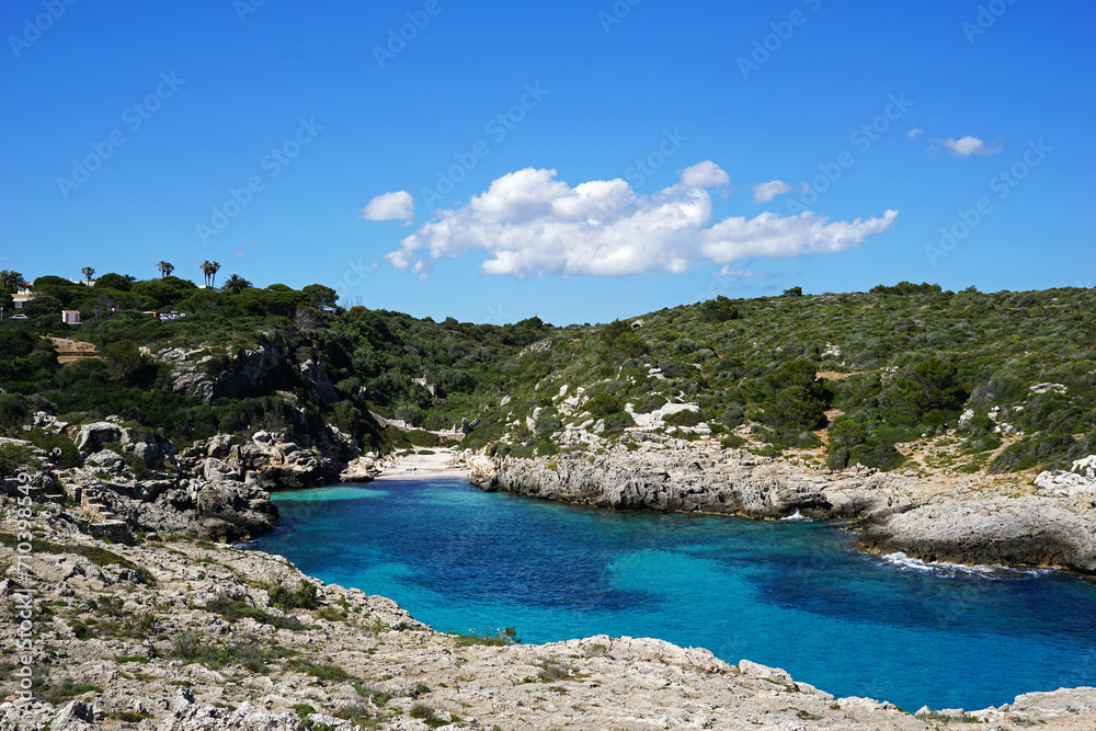 Natural landscape of crystal clear Minorca seascape bay with rocky seashore cliff and blue sky at Cala Binidali beach, Balearic Islands located in Menorca, Spain