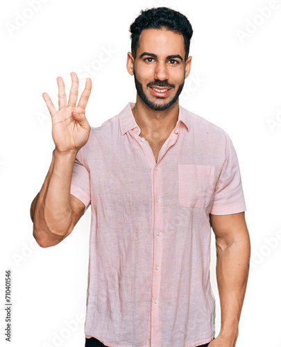 Hispanic man with beard wearing casual shirt showing and pointing up with fingers number four while smiling confident and happy. © Krakenimages.com