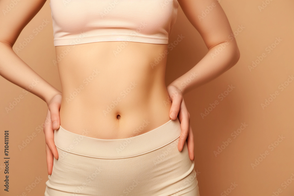 flat athletic belly of a young woman on a beige background, close-up