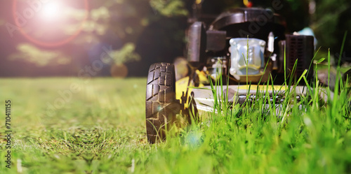 Lawn mower cut grass. Garden work. Electric Rotary lawn mower machine. Panorama, banner photo