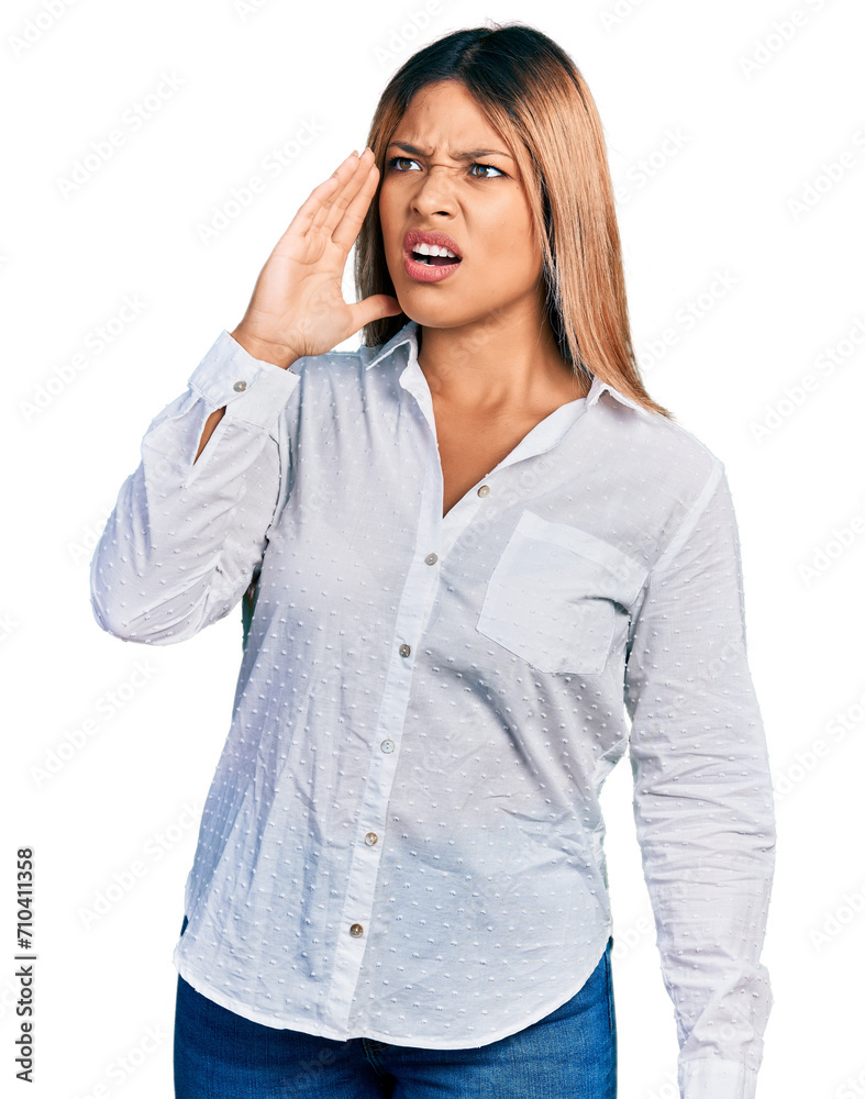Young hispanic woman wearing casual white shirt shouting and screaming loud to side with hand on mouth. communication concept. Young hispanic woman wearing casual white shirt shouting and screaming loud to side with hand on mouth. communication concept.
