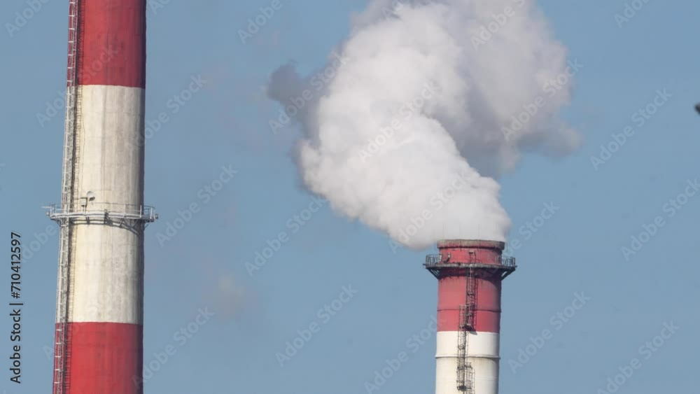 Two industrial smokestacks release steam against a blue sky, symbolizing energy production and environmental impact Two industrial smokestacks release steam against a blue sky, symbolizing energy production and environmental impact