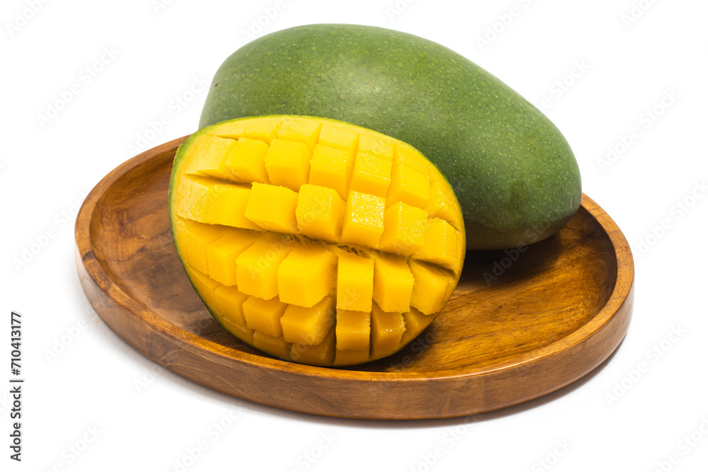 Cut into cubes and whole fresh organic green mango delicious fruit side view in a wooden plate isolated on white background clipping path