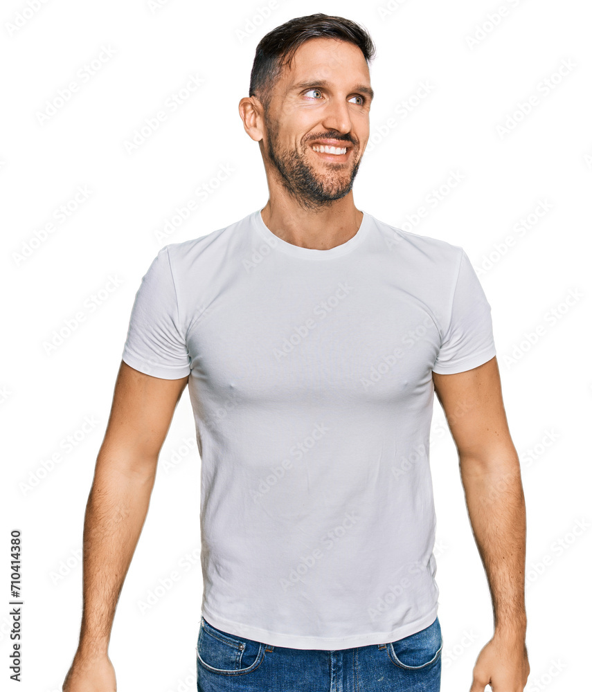 Handsome man with beard wearing casual white t shirt looking away to side with smile on face, natural expression. laughing confident. Handsome man with beard wearing casual white t shirt looking away to side with smile on face, natural expression. laughing confident.