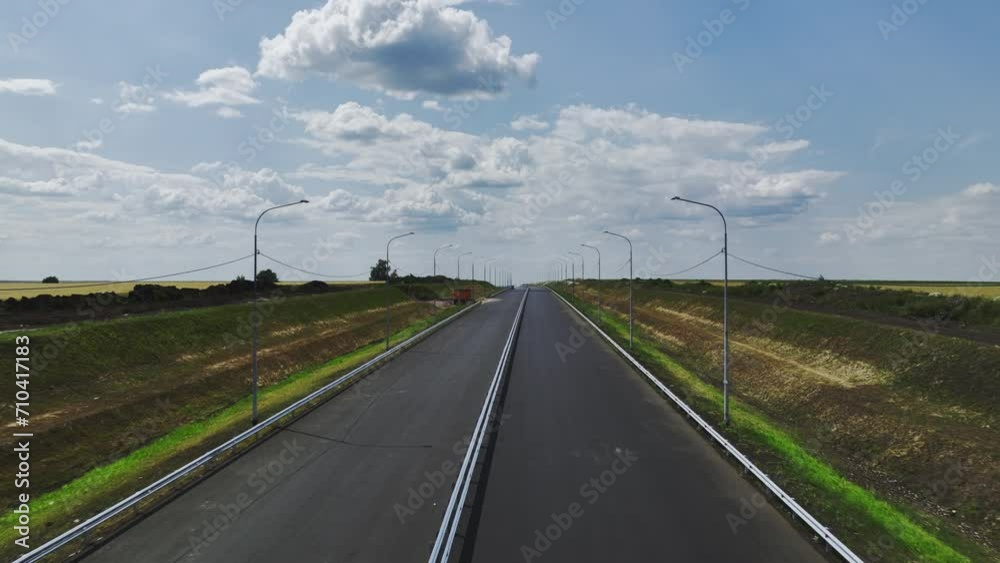 Completely new two-lane highway far away from urban center. Long road with streetlights surrounded by wide country fields primed for utilization Completely new two-lane highway far away from urban center. Long road with streetlights surrounded by wide country fields primed for utilization
