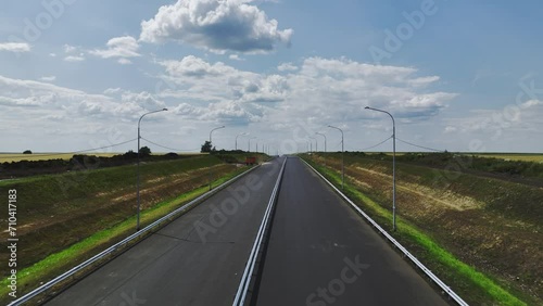 Completely new two-lane highway far away from urban center. Long road with streetlights surrounded by wide country fields primed for utilization photo