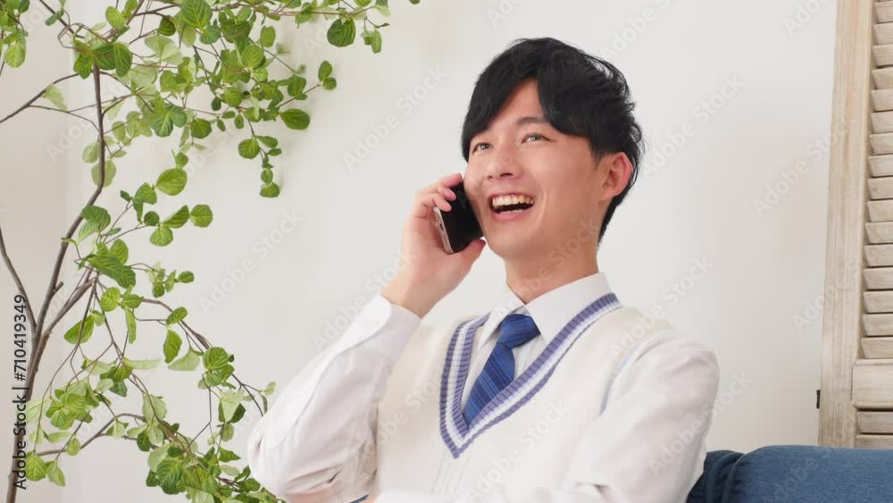 リビングスマートフォンで電話する男子高校生