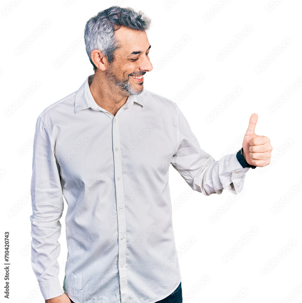 Middle age hispanic with grey hair wearing casual white shirt looking proud, smiling doing thumbs up gesture to the side Middle age hispanic with grey hair wearing casual white shirt looking proud, smiling doing thumbs up gesture to the side