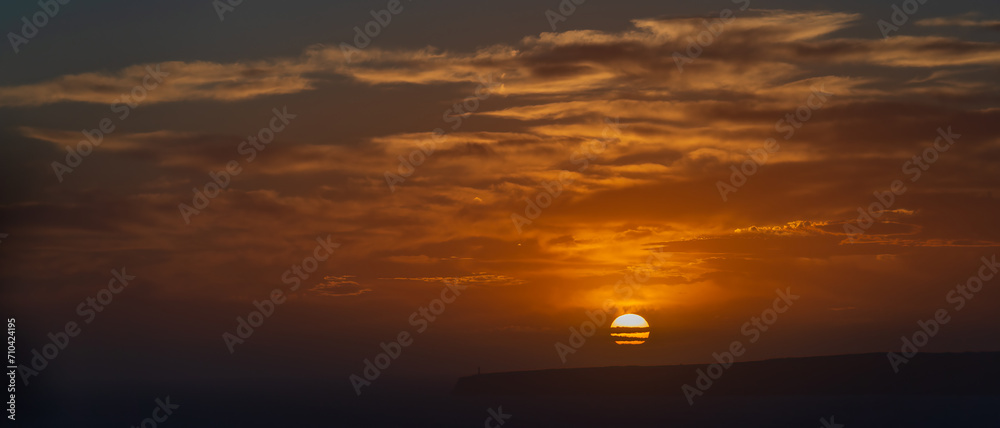 Majestic Sunset Silhouette of Lighthouse on Seaside Cliffs Under the Orange Sky