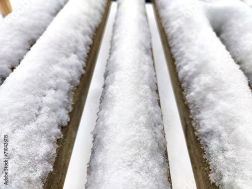 Snow on the crossbars of wooden bench. Abstract background, texture, pattern, frame, place for text and copy space