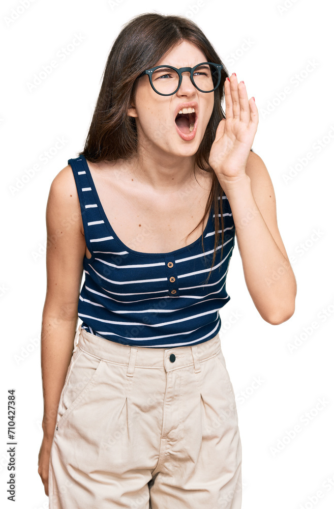 Young beautiful caucasian girl wearing casual clothes and glasses shouting and screaming loud to side with hand on mouth. communication concept. Young beautiful caucasian girl wearing casual clothes and glasses shouting and screaming loud to side with hand on mouth. communication concept.