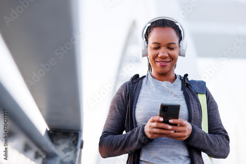 Woman using smart phone and listening to the music while going for morning workout photo