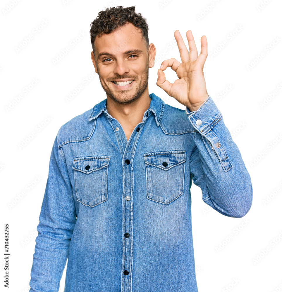 Young hispanic man wearing casual denim jacket smiling positive doing ok sign with hand and fingers. successful expression. Young hispanic man wearing casual denim jacket smiling positive doing ok sign with hand and fingers. successful expression.