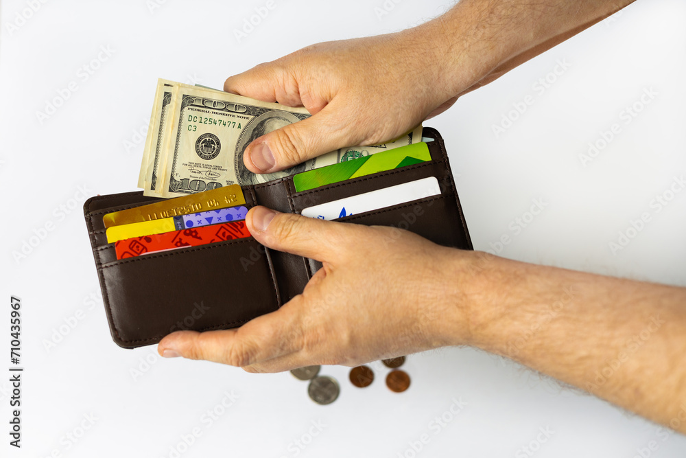 Close up male hand open the wallet. He has lot money us dollar in wallet. A man puts American dollars in her wallet. A male is holding an American bills. Isolated on white. Close up male hand open the wallet. He has lot money us dollar in wallet. A man puts American dollars in her wallet. A male is holding an American bills. Isolated on white.