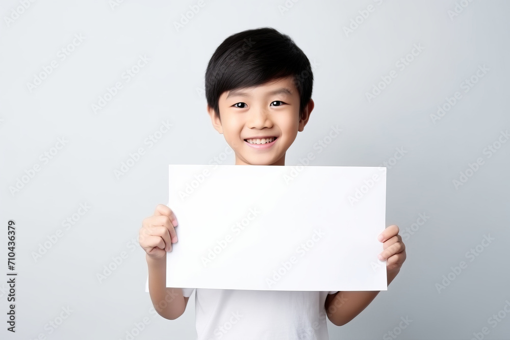 Happy Asian Scholl boy holding blank white banner sign, isolated studio portrait . Happy Asian Scholl boy holding blank white banner sign, isolated studio portrait .