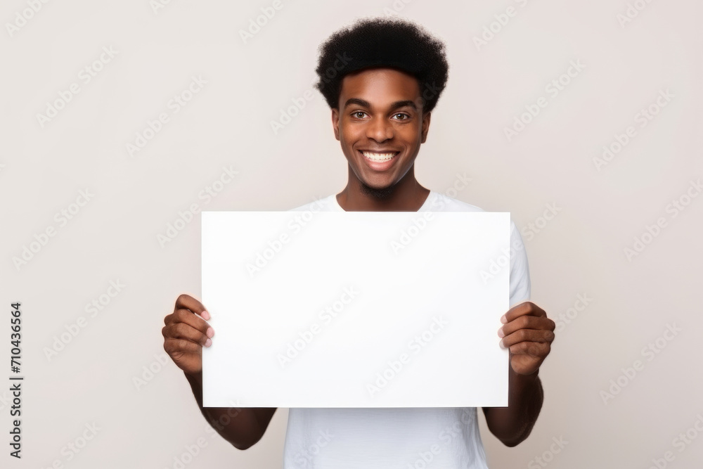 Happy young black man holding blank white banner sign, isolated studio portrait. Happy young black man holding blank white banner sign, isolated studio portrait.