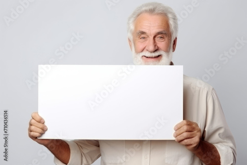 Happy old man holding blank white banner sign, isolated studio portrait.