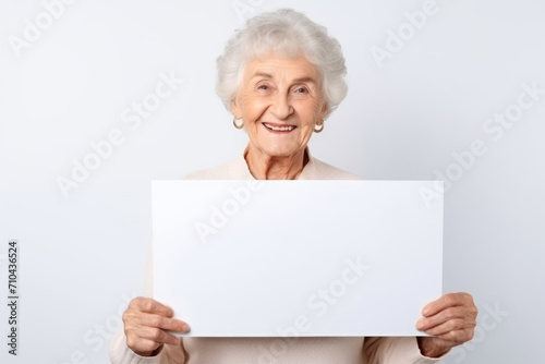 Happy old woman holding blank white banner sign, isolated studio portrait.
